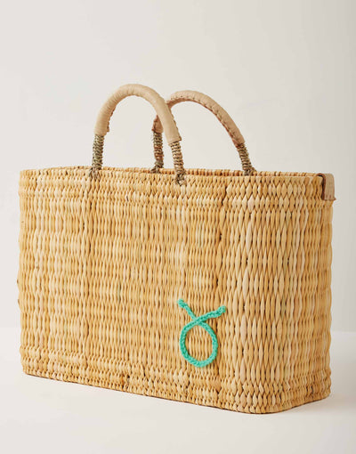 Market straw basket with tan leather handles and Taurus symbol embroidered in foam green