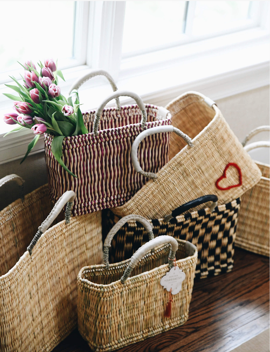 collection of straw bags stacked on top of each other near a window