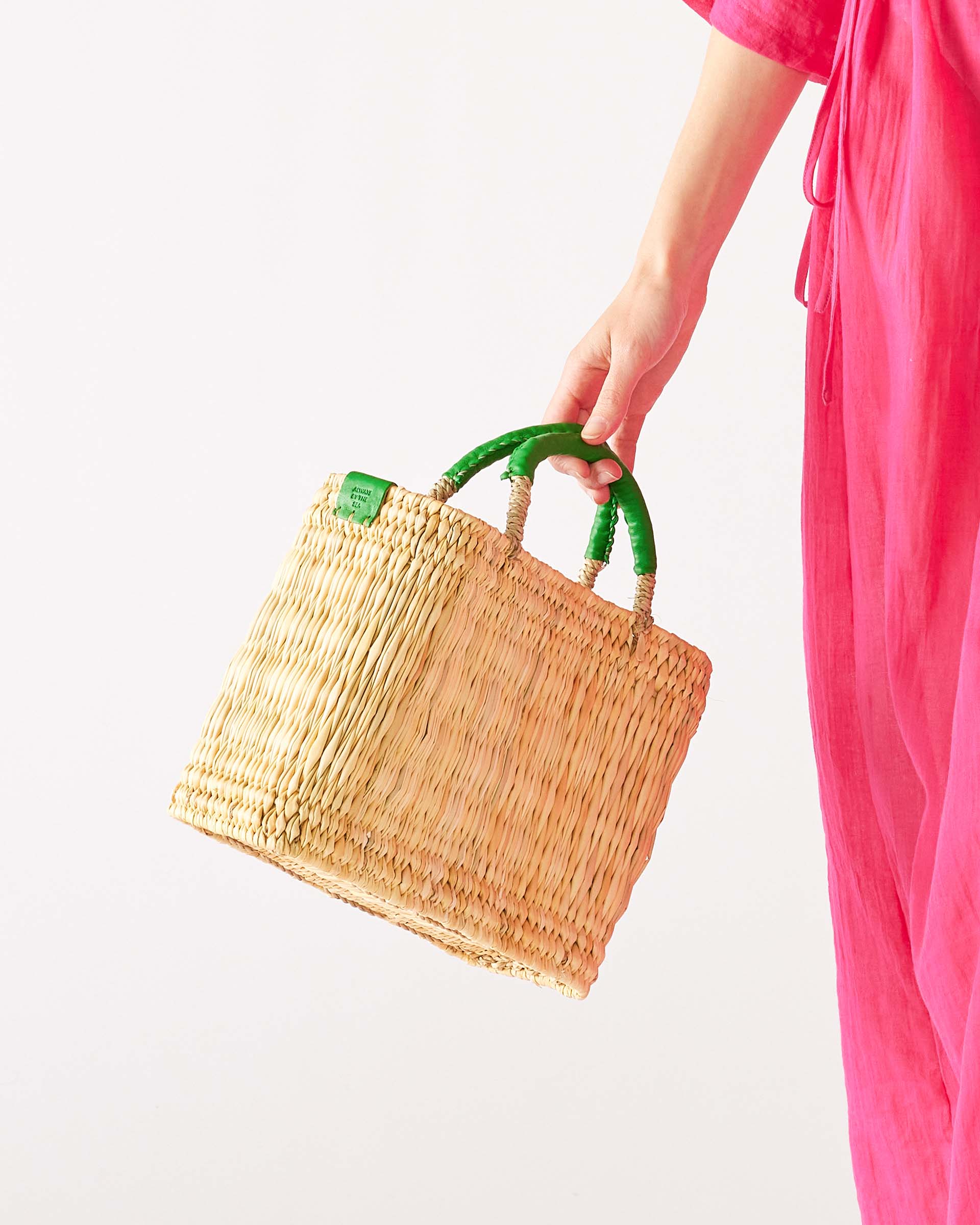 woman in pink dress holding medina nasket with green handles