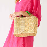 woman in pink dress holding medina market basket with green handles