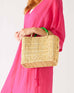 woman in pink dress holding medina market basket with green handles