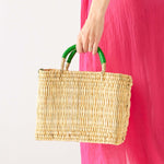 woman holding medina market basket with green handles