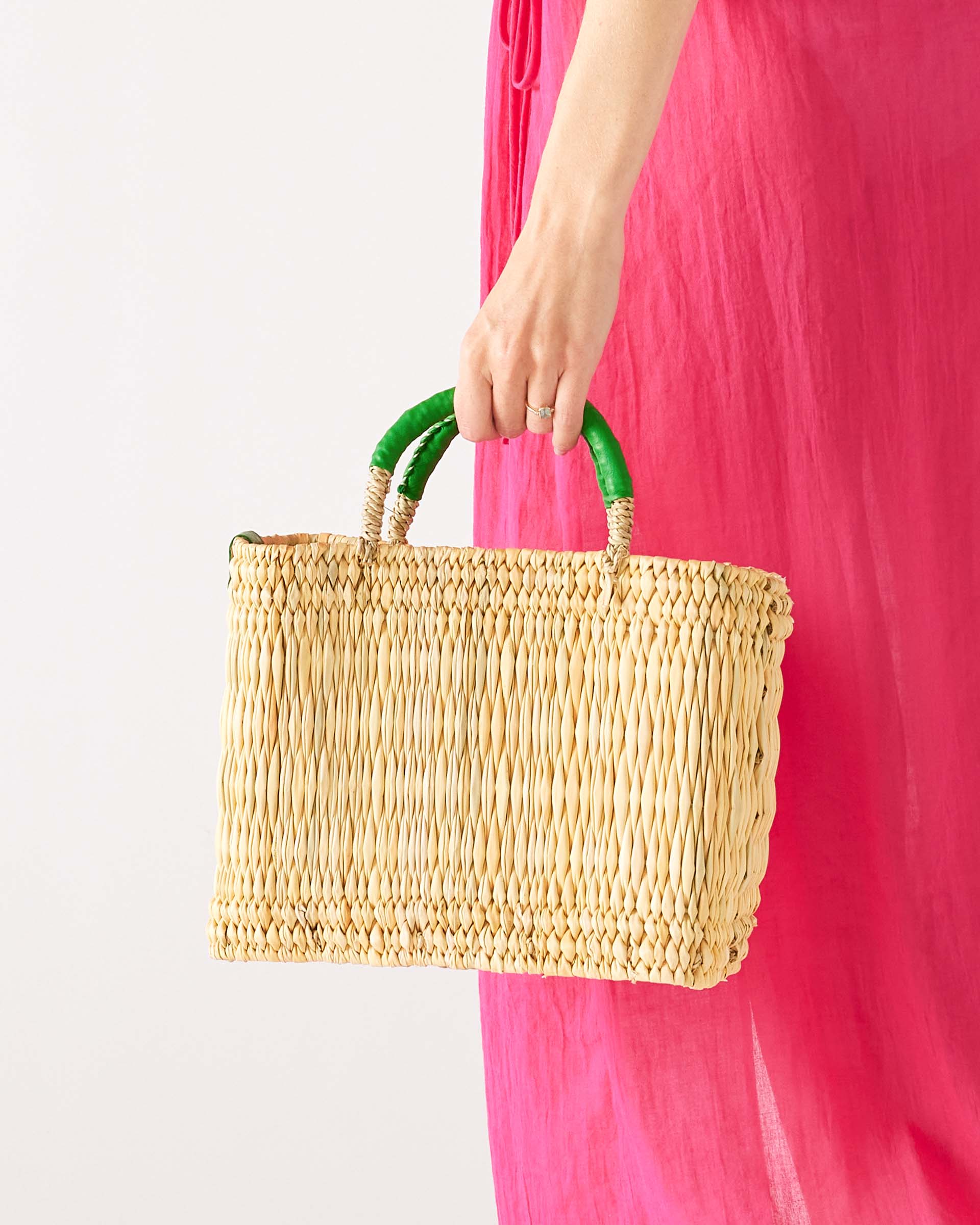 woman holding medina market basket with green handles