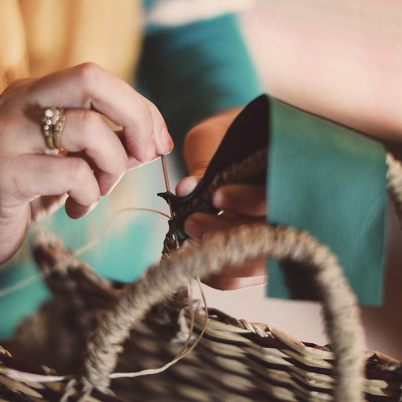 Green Leather being Hand Stitched onto Handles of Straw Handbag