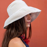 Woman wearing a white sun hat against a red background