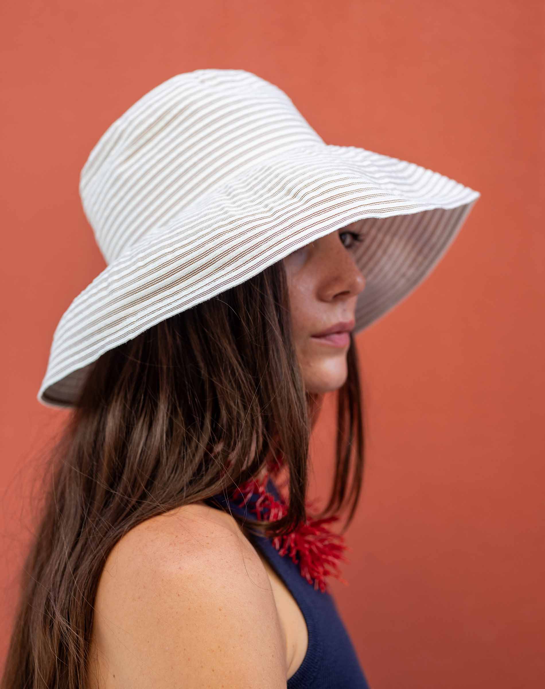 Woman wearing a white sun hat against a red background