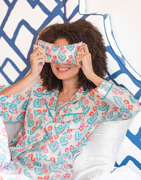 woman holding eye pillow over eyes in block print poppy pattern