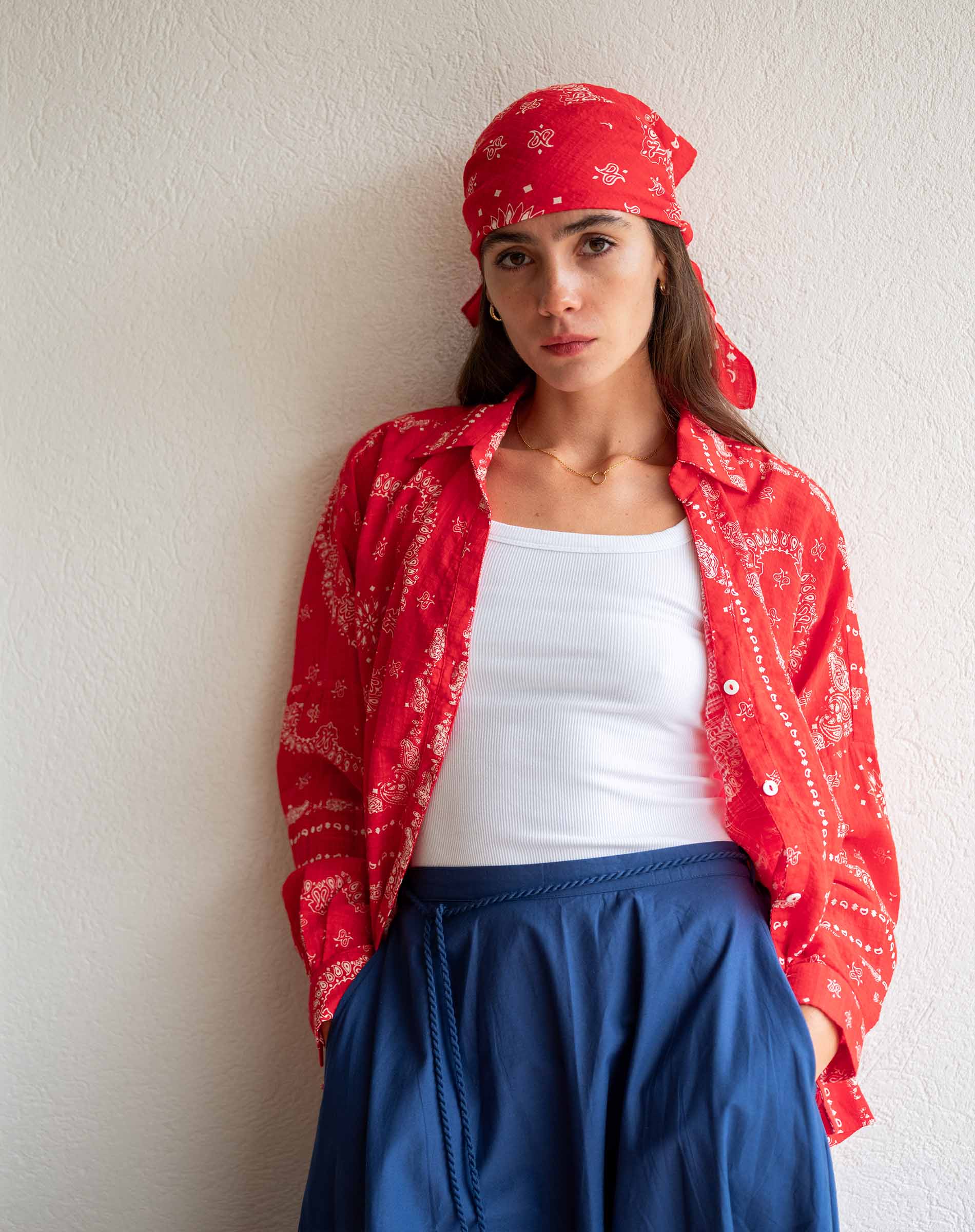 Woman wearing a red bandana and red jacket against a white wall