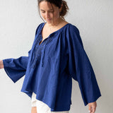 Woman wearing a blue blouse and white shorts against a plain background