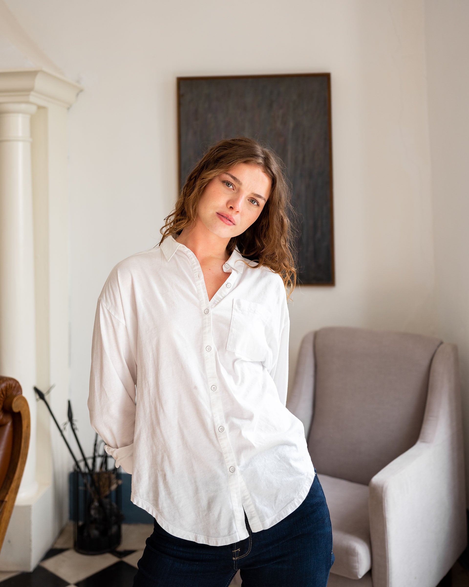 woman showcasing white mersea modern oxford tee button down standing in living room