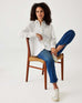 woman showcasing white mersea modern oxford tee button down sitting on chair