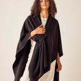 Woman wearing a dark purple poncho against a plain background