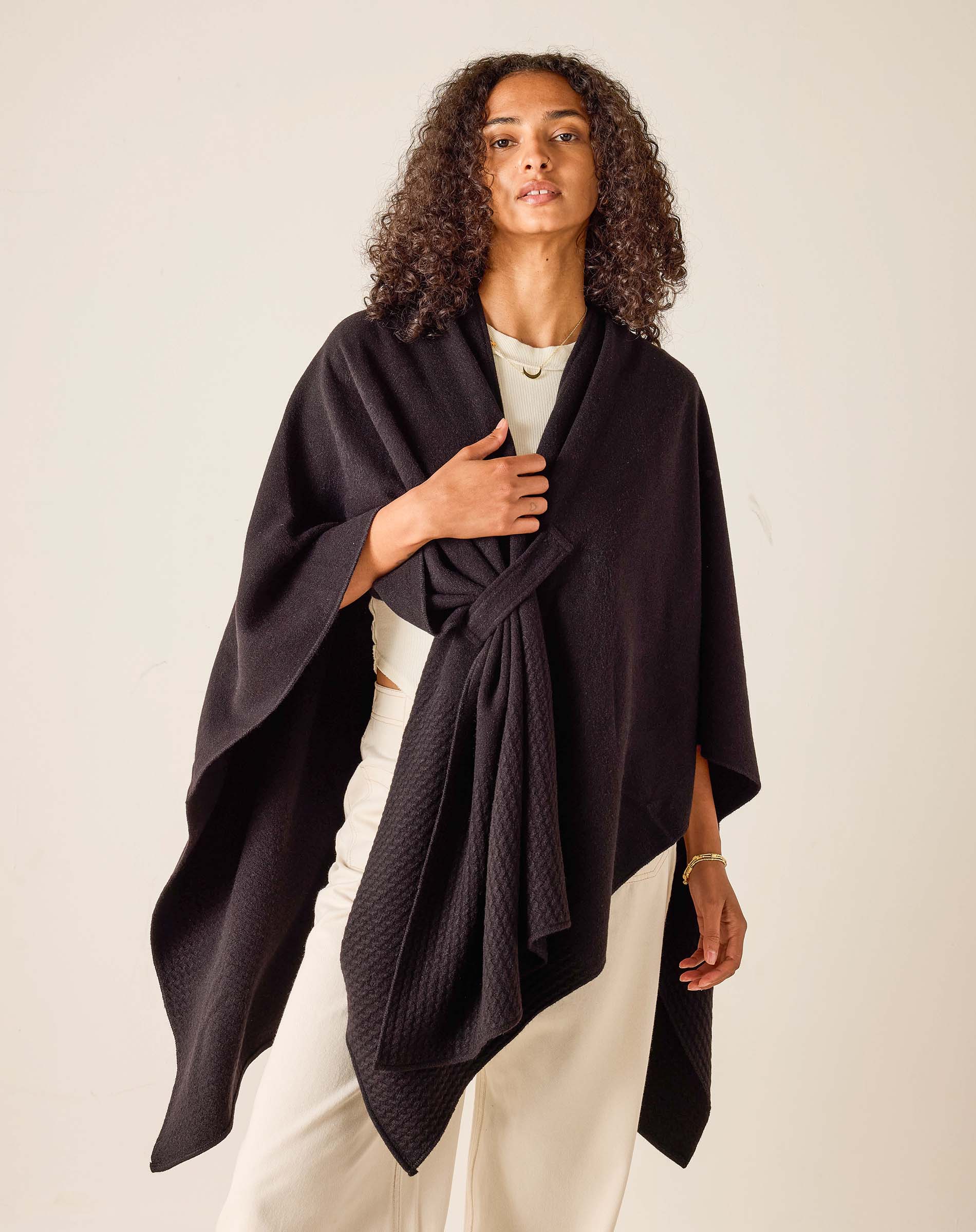 Woman wearing a dark purple poncho against a plain background