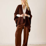 MERSEA ladies' travel-ready women's travel-friendly chocolate ribbed knit travel wrap worn over a light-colored button-down shirt and wide-leg trousers.
