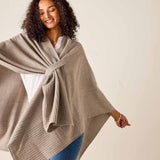 Woman wearing a beige poncho against a plain background