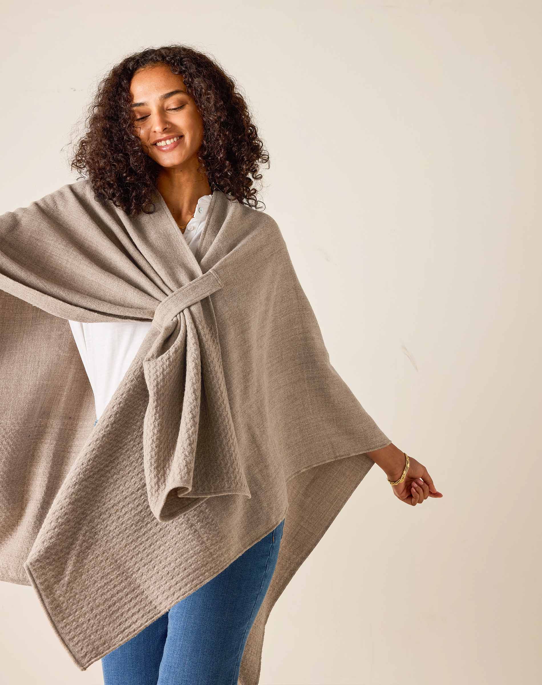 Woman wearing a beige poncho against a plain background