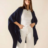 Woman wearing a navy blue cardigan over a white outfit on a beige background