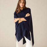 Woman wearing a navy blue poncho against a beige background