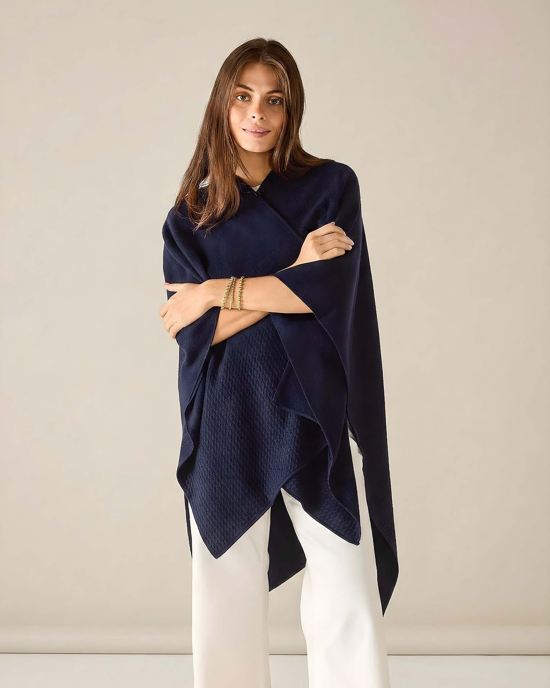 Woman wearing a navy blue poncho against a beige background