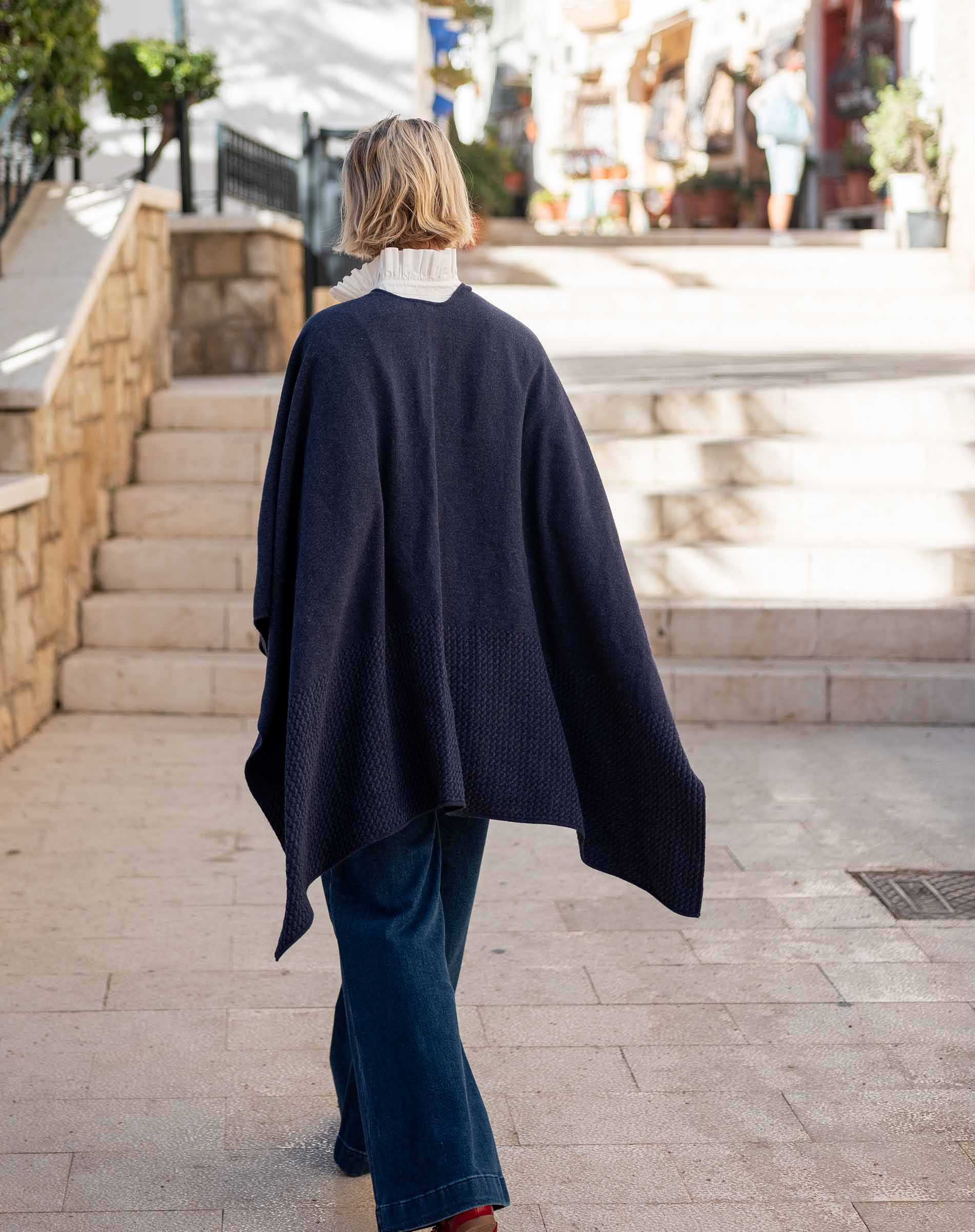 Ladies' travel-ready back view of the navy textured knit travel wrap over a white collar and dark denim jeans.