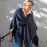 Women's travel-friendly navy waffle-knit travel wrap draped over a white blouse and blue denim jeans.