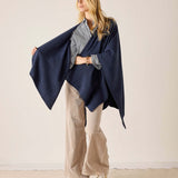 Navy blue waffle-texture travel wrap worn over a grey top and beige wide-leg trousers.