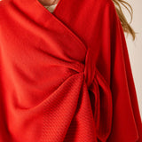 Red wrap garment with a knot detail on a neutral background
