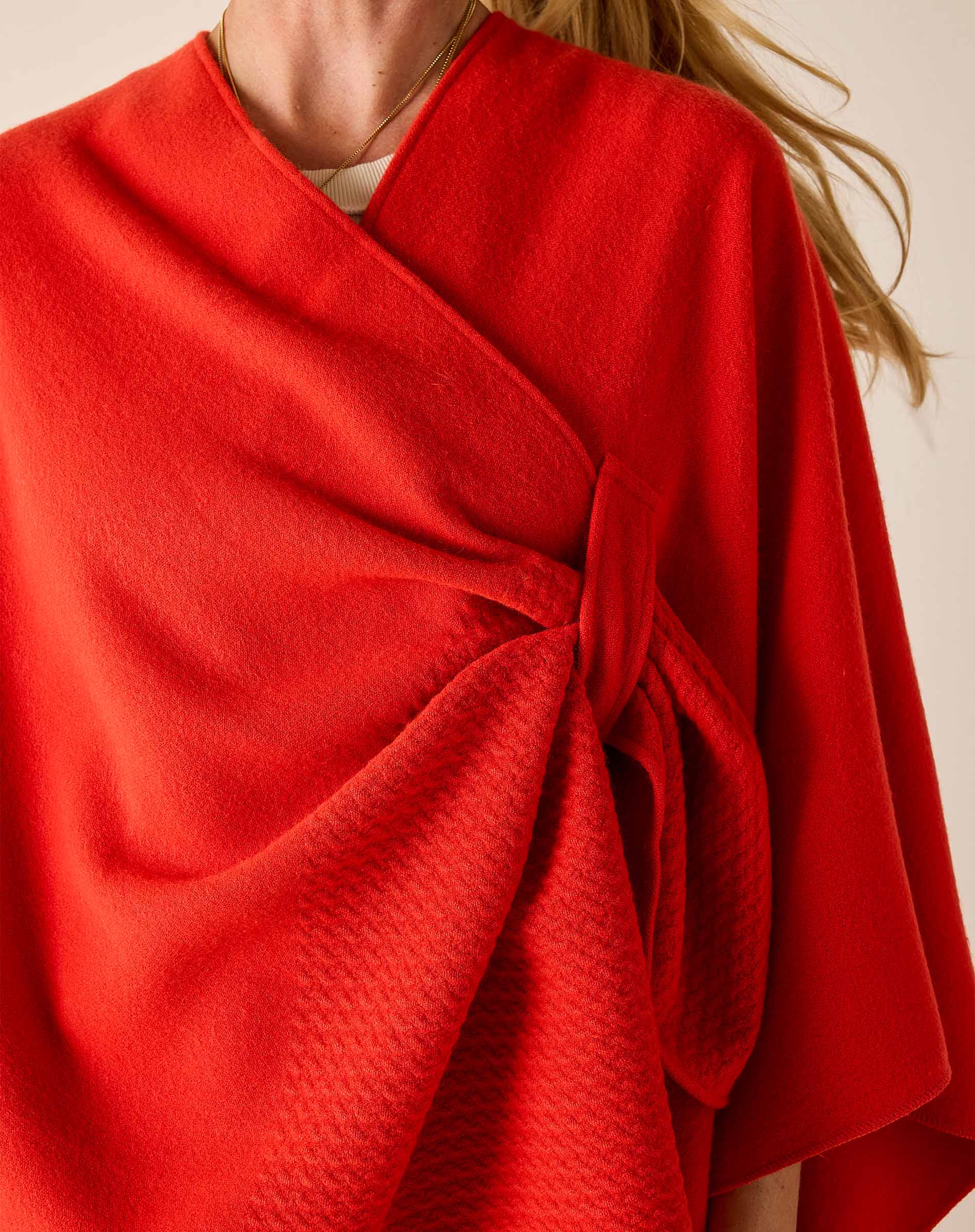 Red wrap garment with a knot detail on a neutral background