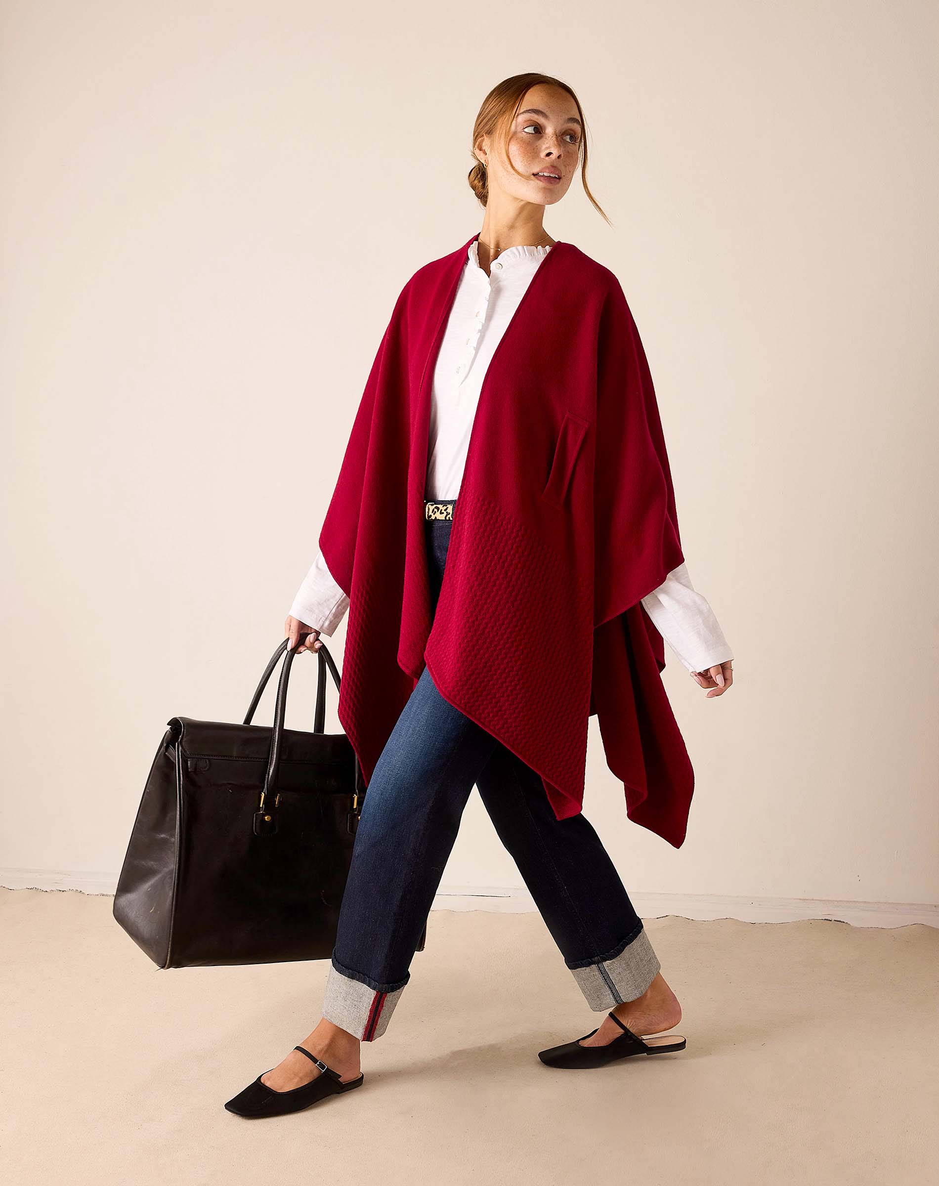 Wine-colored knit travel wrap featuring a draped silhouette and voluminous folds.