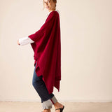 Wine colored ribbed knit travel wrap worn over a white long-sleeved top and dark pants.