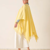Woman wearing a yellow shawl over a white outfit on a beige background
