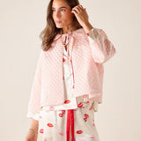 Woman wearing a pink patterned outfit with a plain background