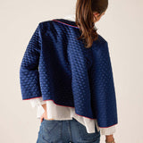 Person wearing a blue quilted jacket on a plain background