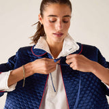 Woman wearing a blue quilted jacket with white lining against a plain background