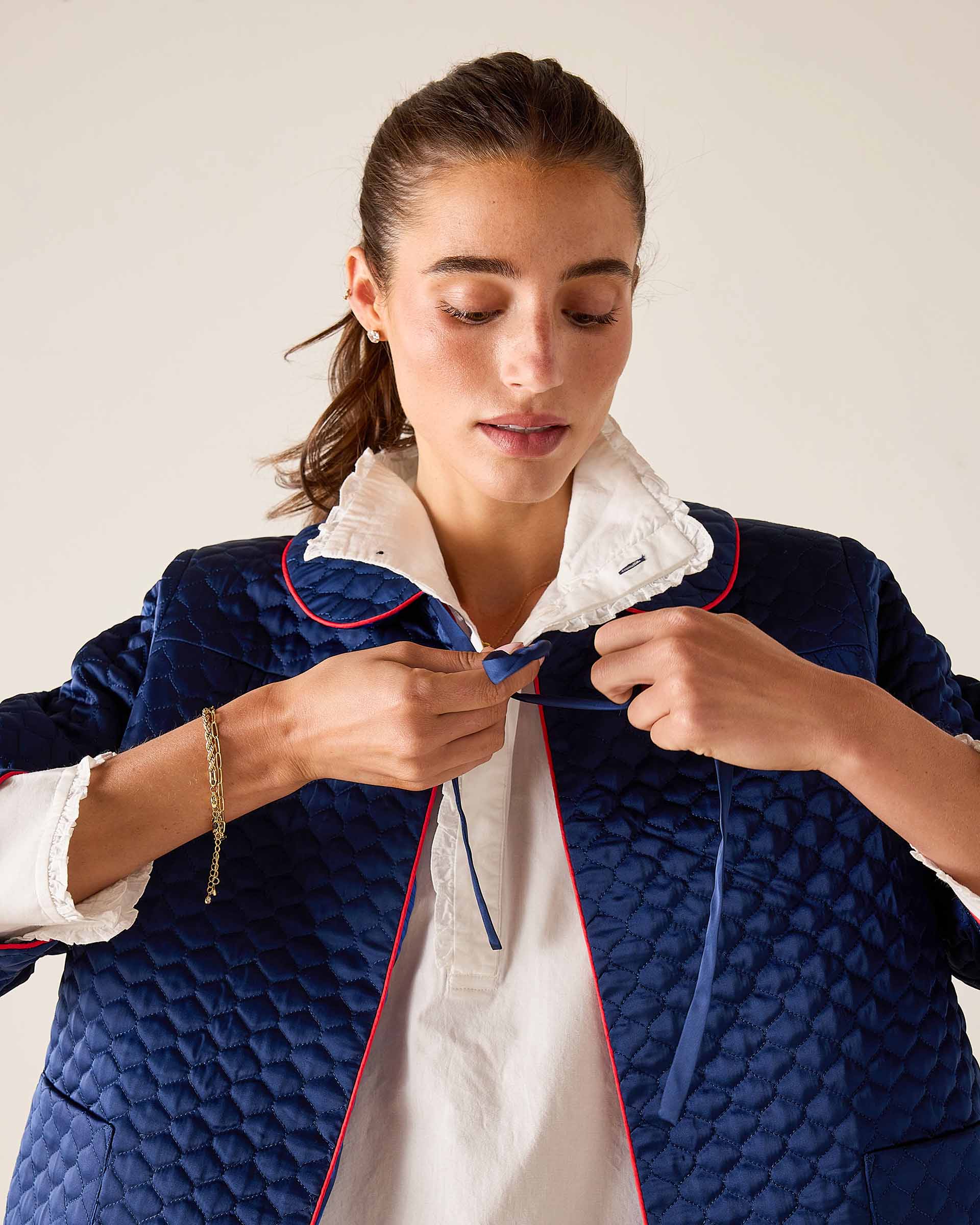 Woman wearing a blue quilted jacket with white lining against a plain background