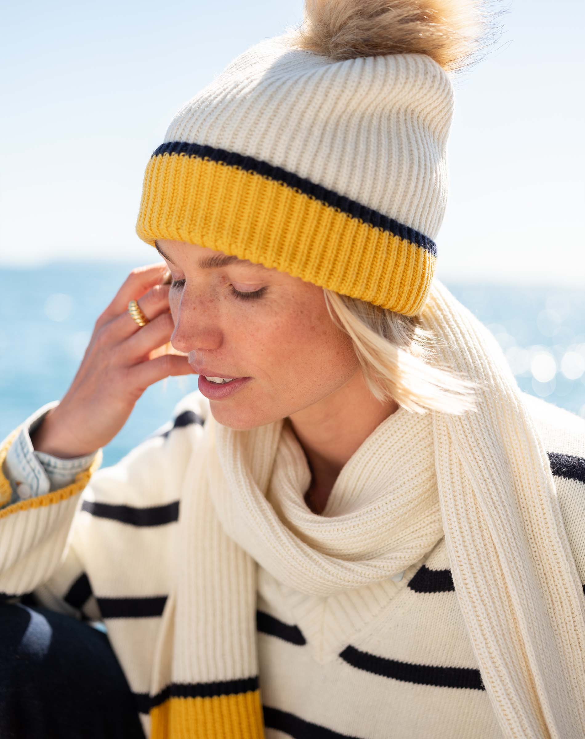 Cream and golden yellow ribbed knit beanie with a large faux fur pom-pom.