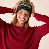 Olive green knit beanie with a decorative stripe and large pom-pom.
