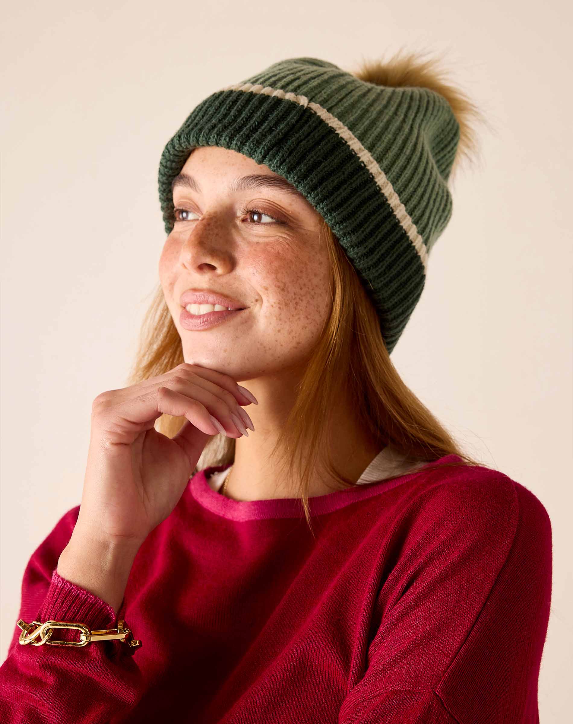 Forest green ribbed knit beanie with a cream stripe and faux fur pom-pom.
