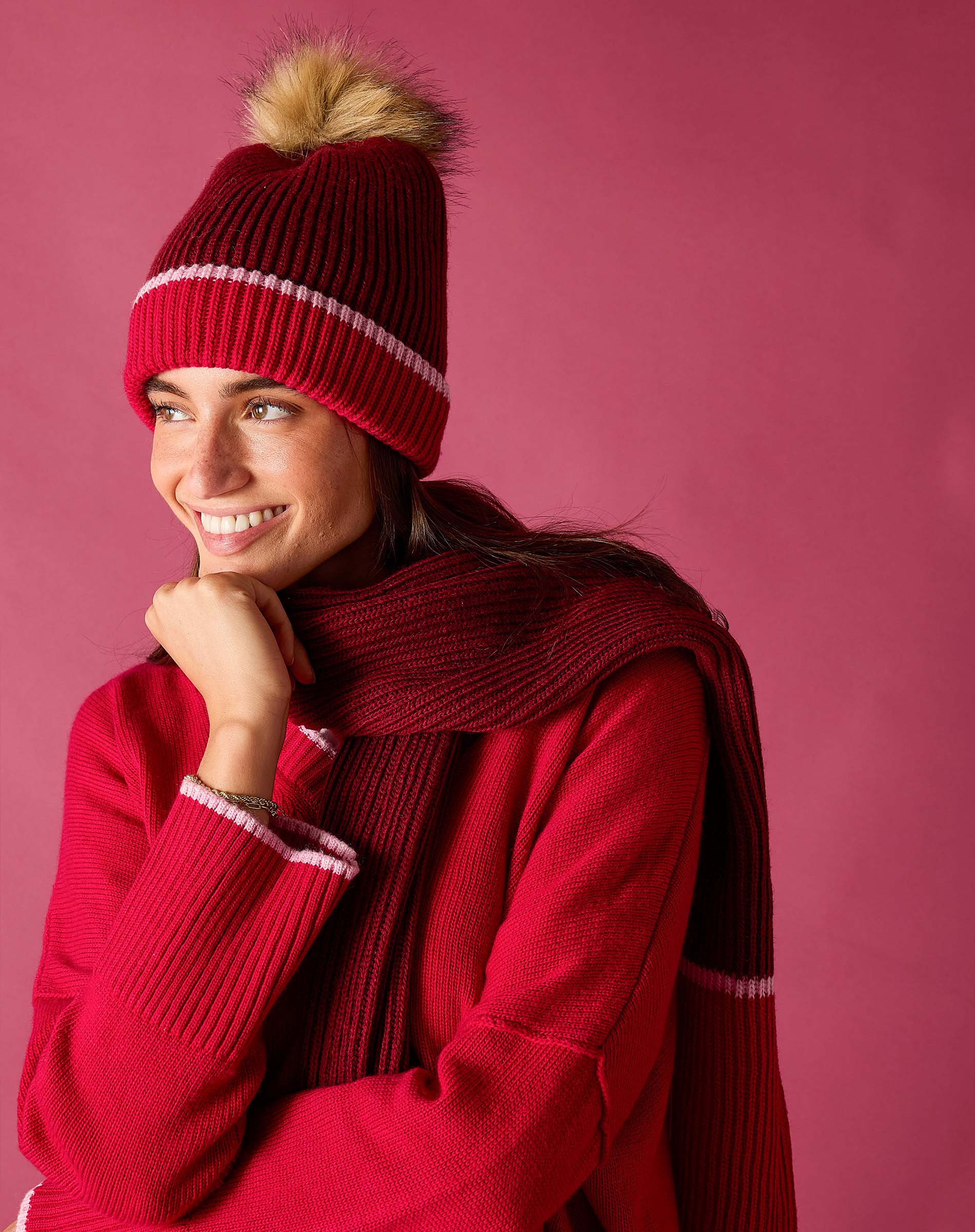 Raspberry pink ribbed knit beanie with a plush faux fur pom-pom.