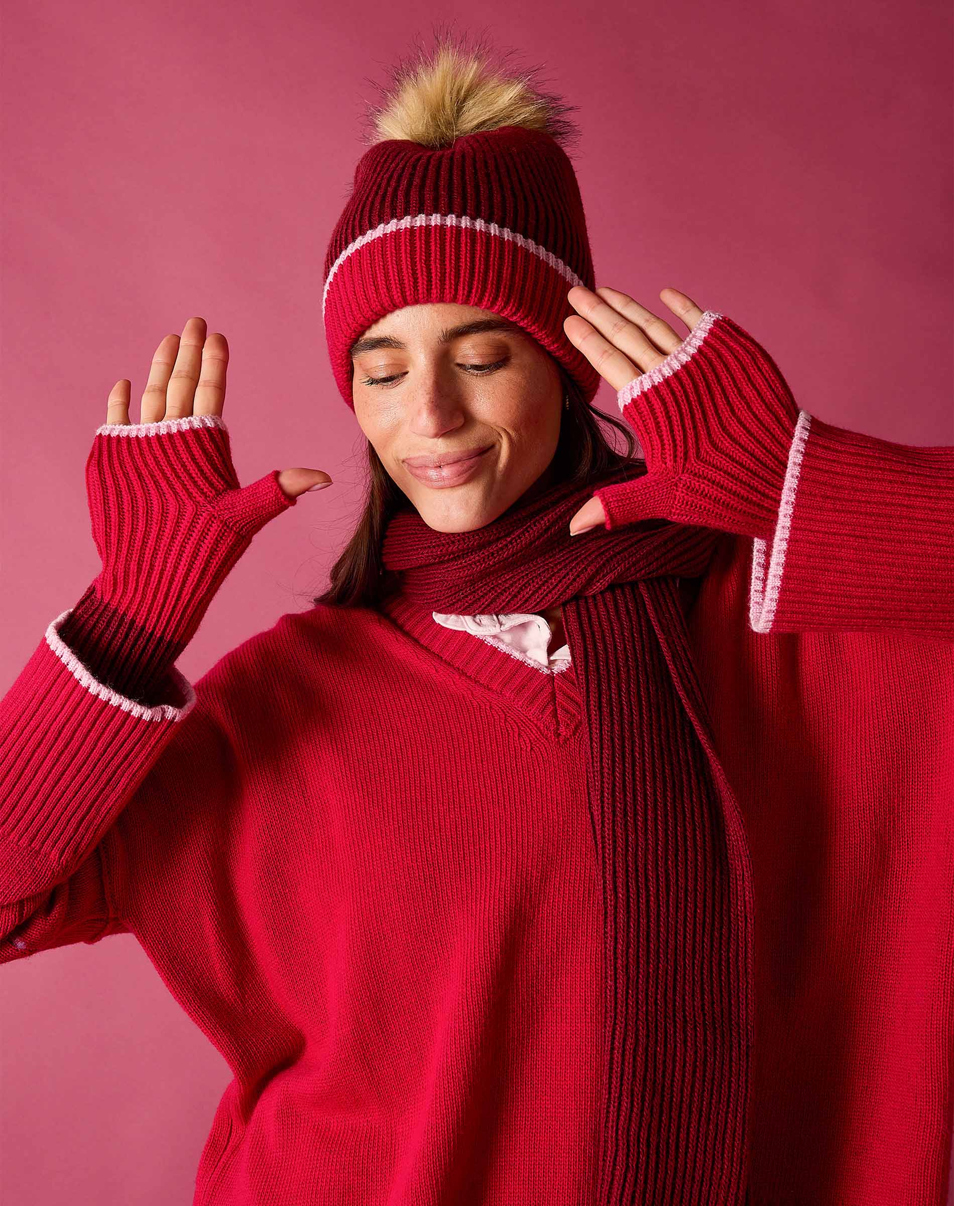 Raspberry pink knit fingerless gloves with white and maroon stripe detail.