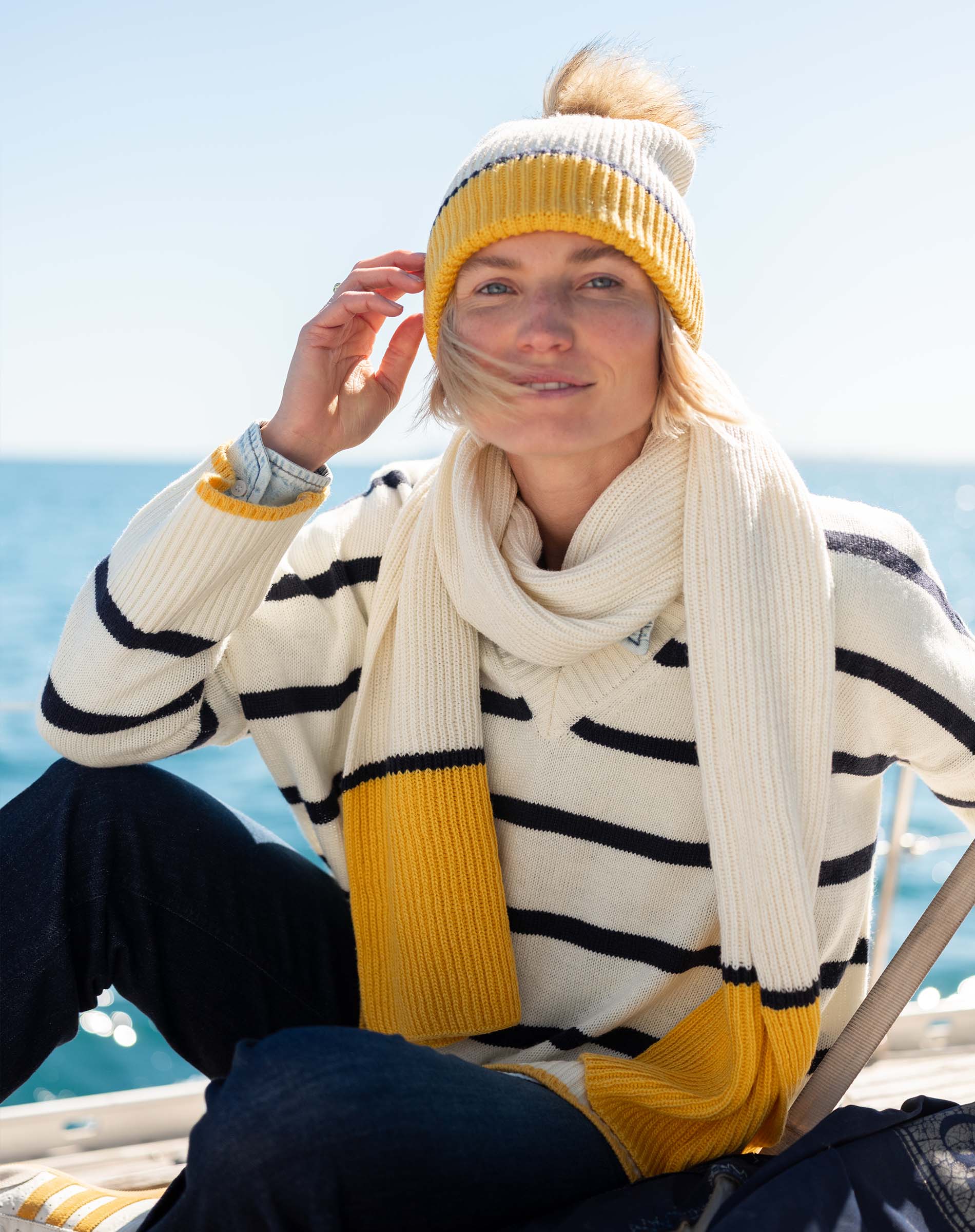 Cream and golden yellow striped knit scarf with oversized fringe.