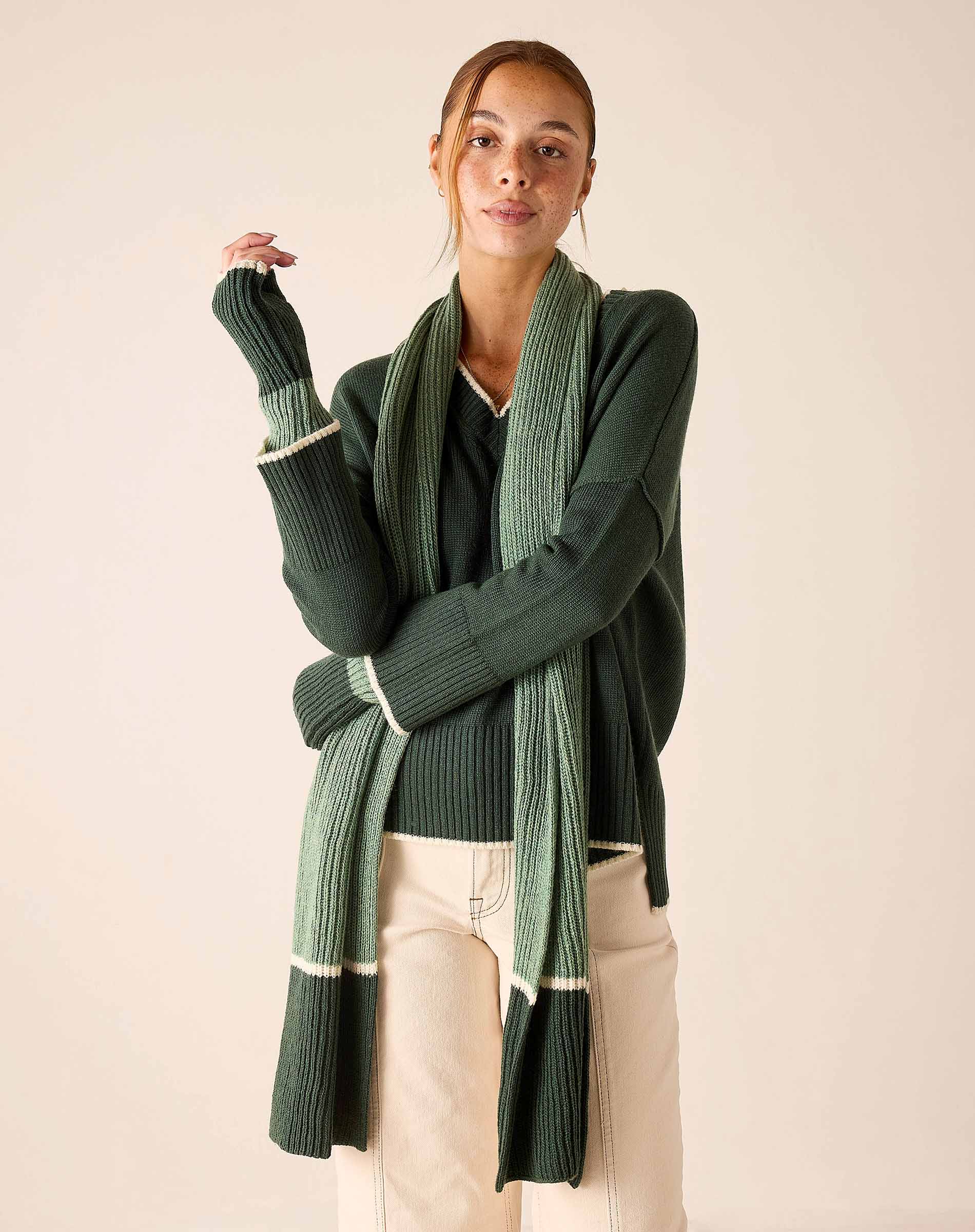 Forest green and cream striped ribbed knit scarf draped over a sweater.