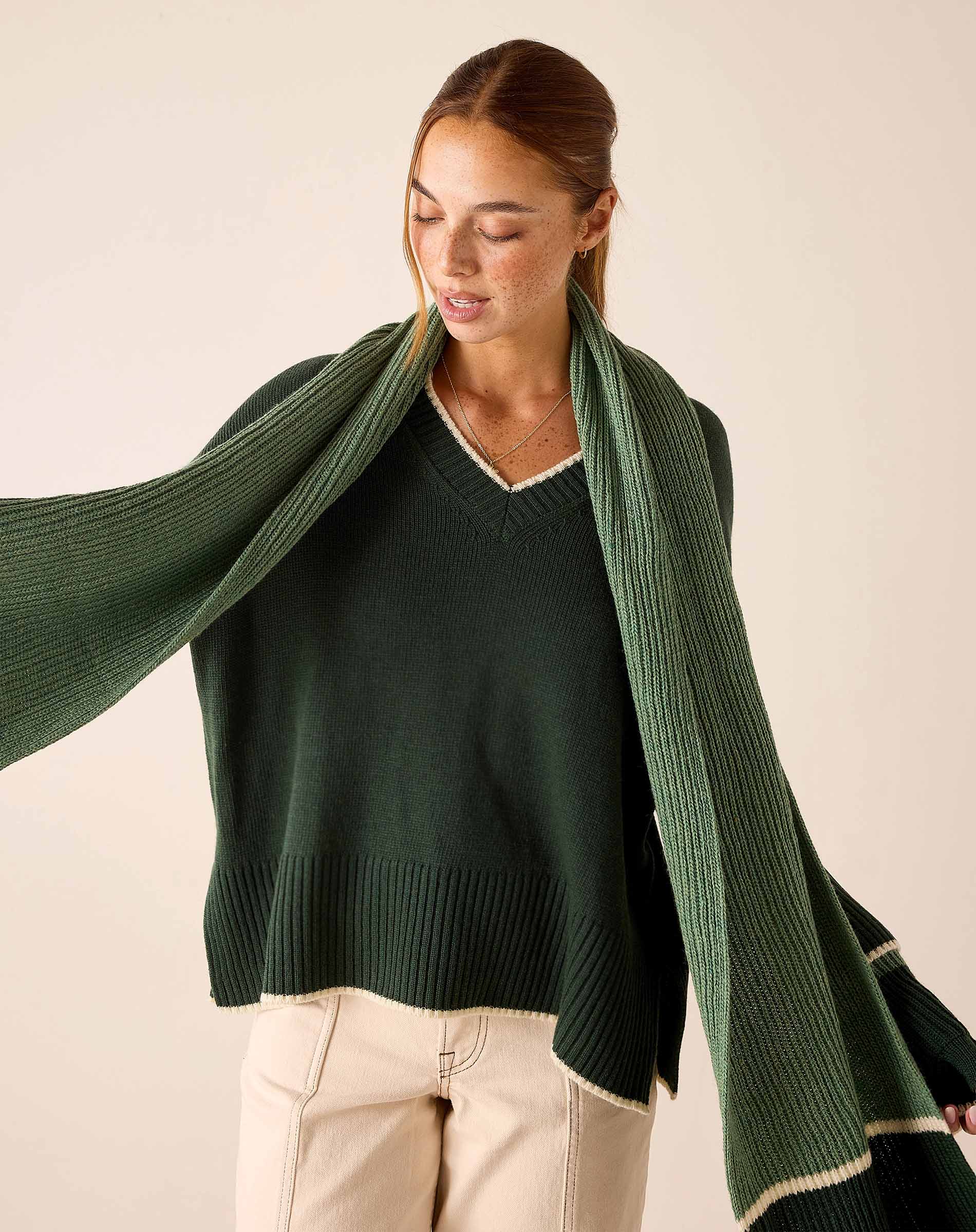 Olive green ribbed knit wrap scarf with frayed hem detail.