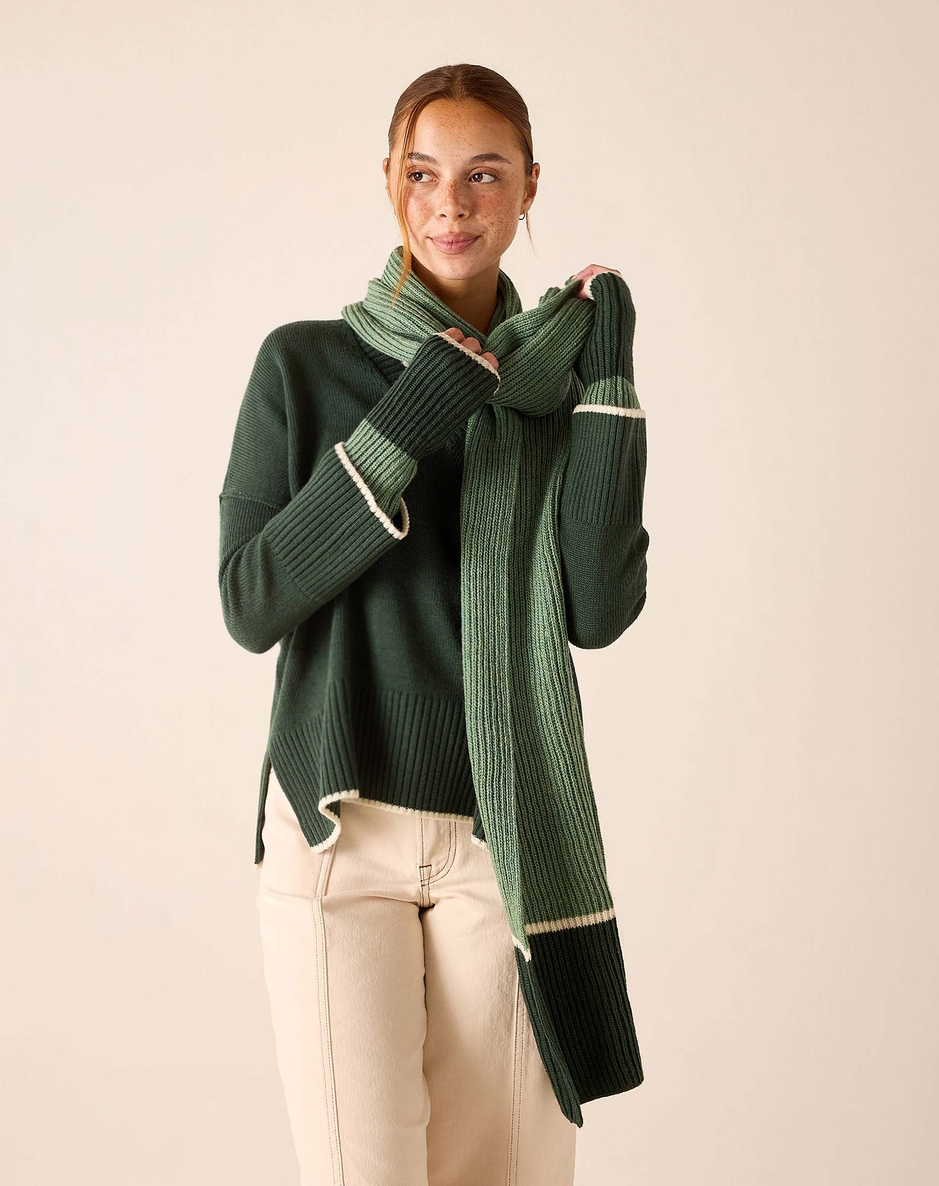 Forest green ribbed knit sweater paired with a matching oversized striped scarf in shades of sage and olive.