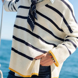 Cream and navy striped knit top with golden trim on a boat.