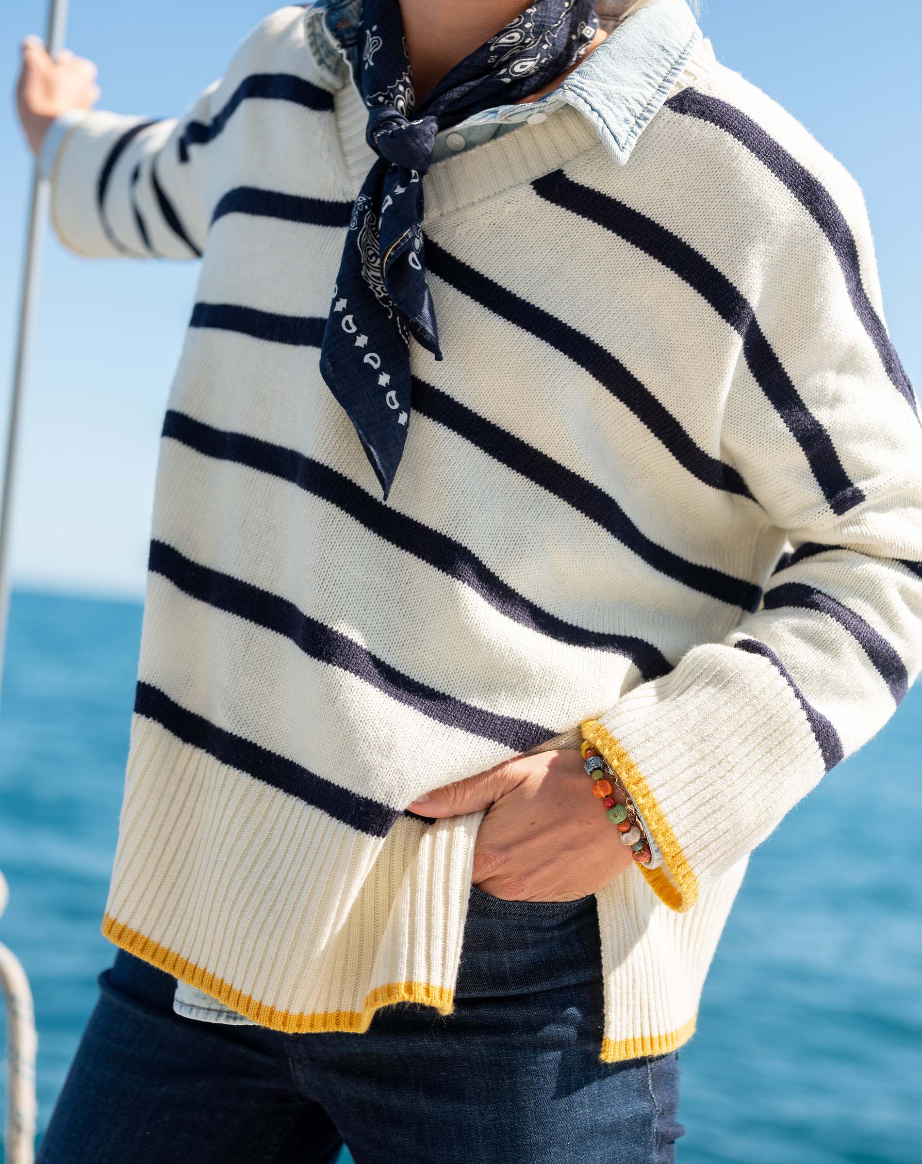 Cream and navy striped knit top with golden trim on a boat.