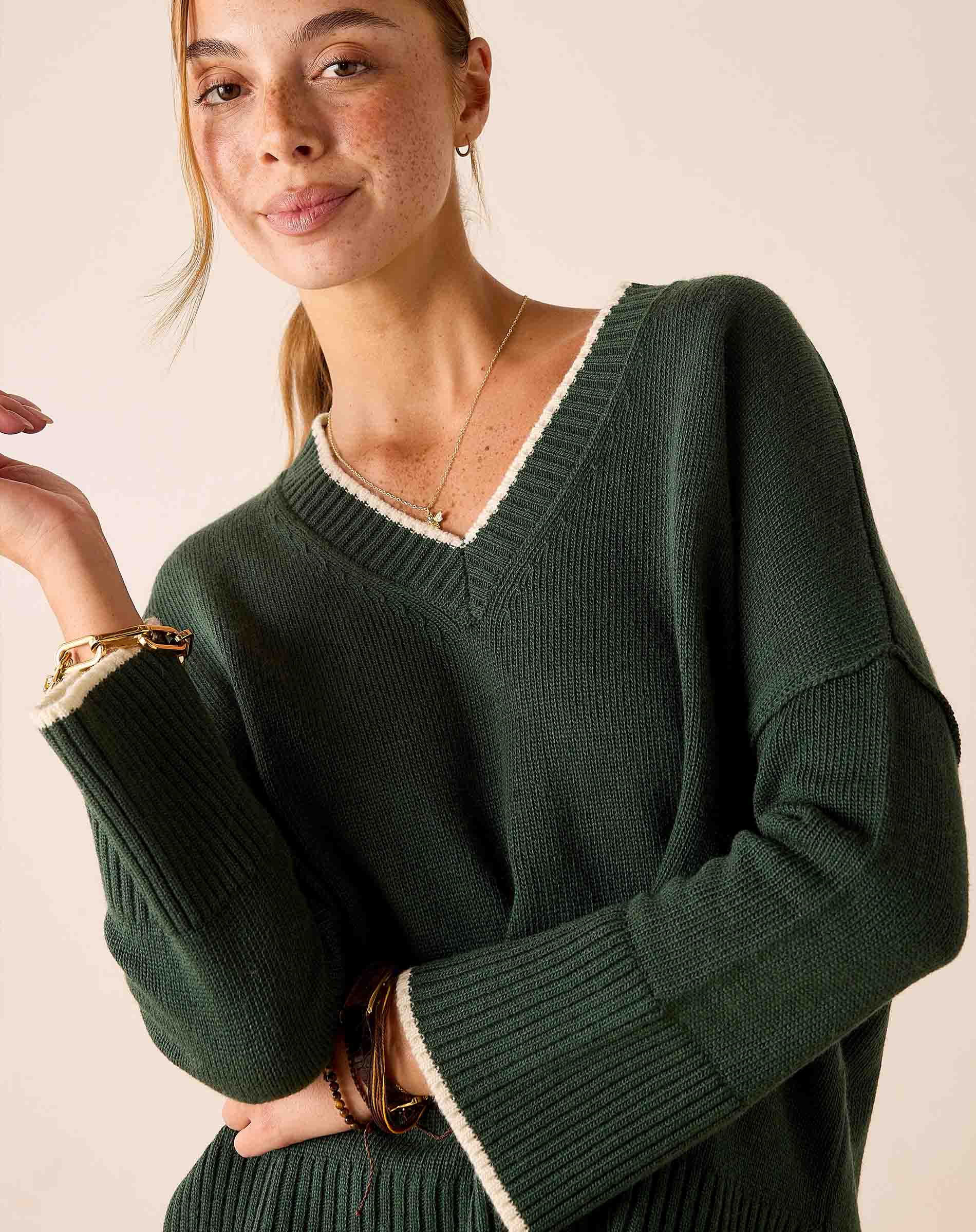 MERSEA ladies' travel-ready forest green V-neck knit sweater with cream trim and textured ribbed finish.