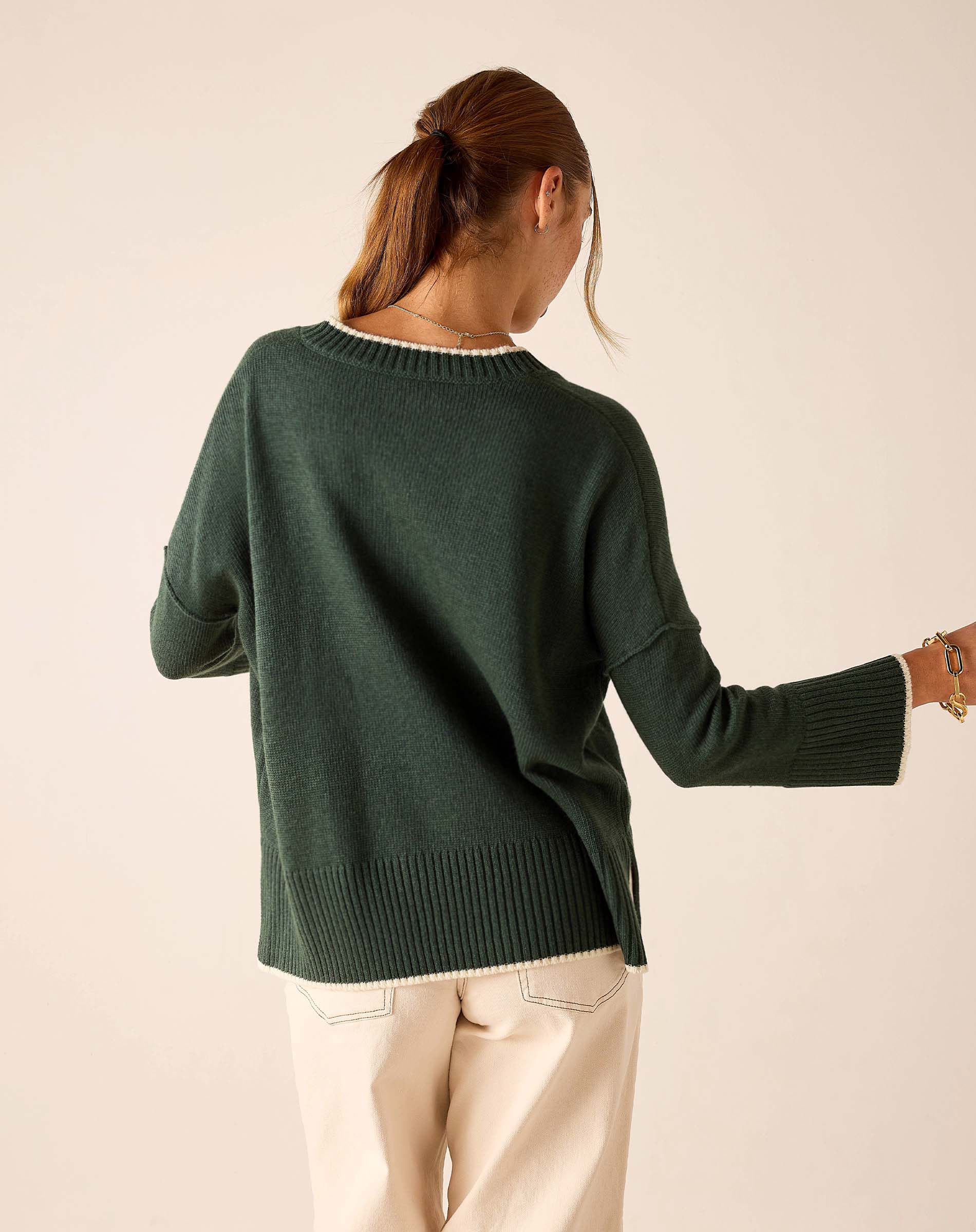 Back view of women's travel-friendly forest green knit top with a ribbed hem and wide sleeves.