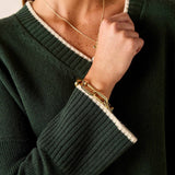 Dark green ribbed knit v-neck sweater with white trim and gold jewelry