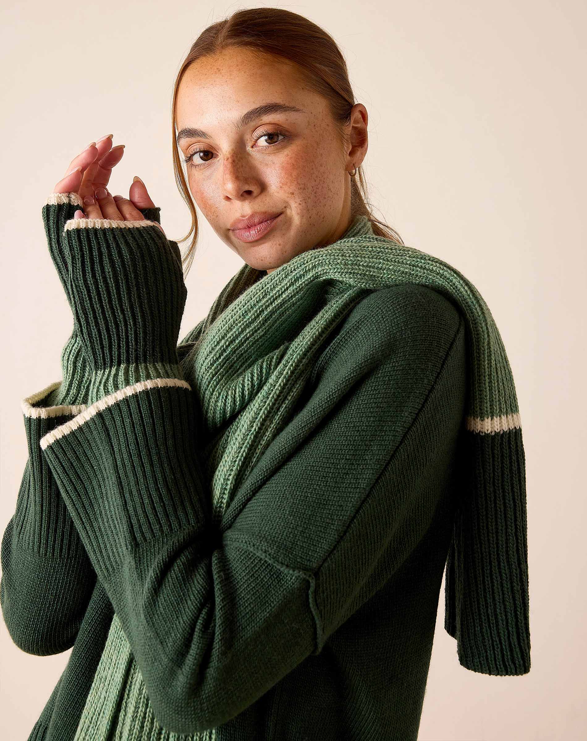 Forest green ribbed knit sweater with a cream stripe detail on the cuffs and hem.